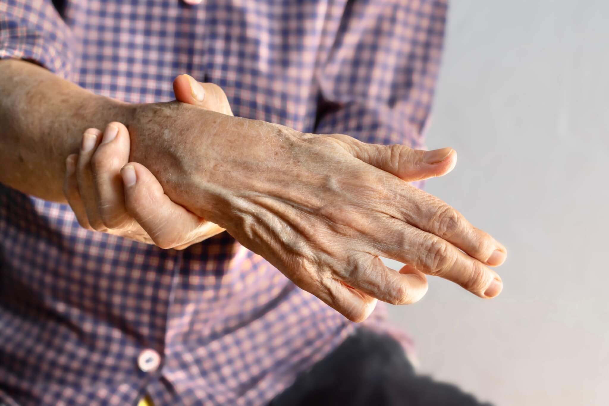 An elderly man experiencing involuntary hand muscle contractions